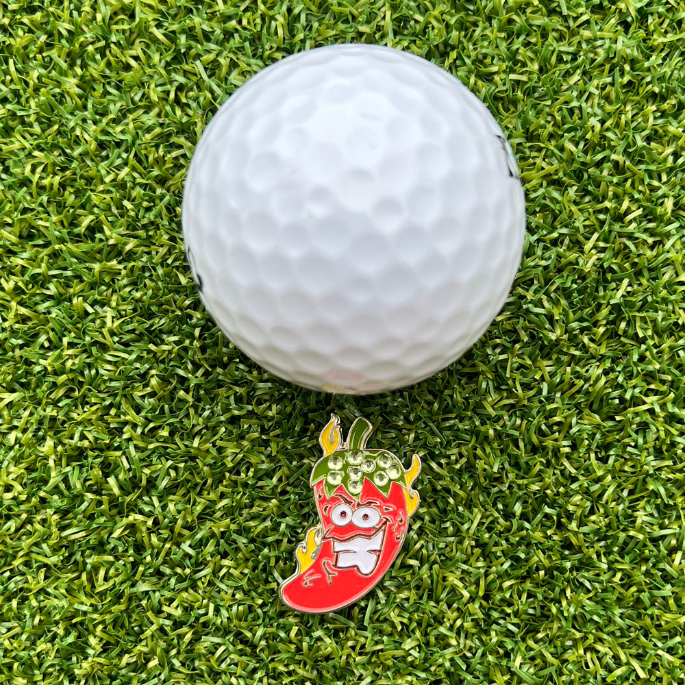 Golf ball on grass with a colorful chili pepper bling ball marker