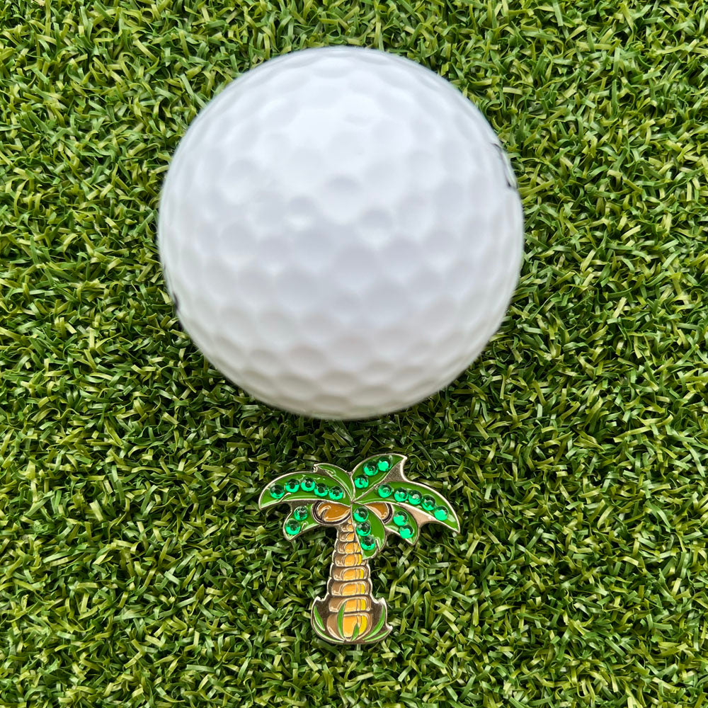 palm tree shaped ball marker with white golf ball on grass