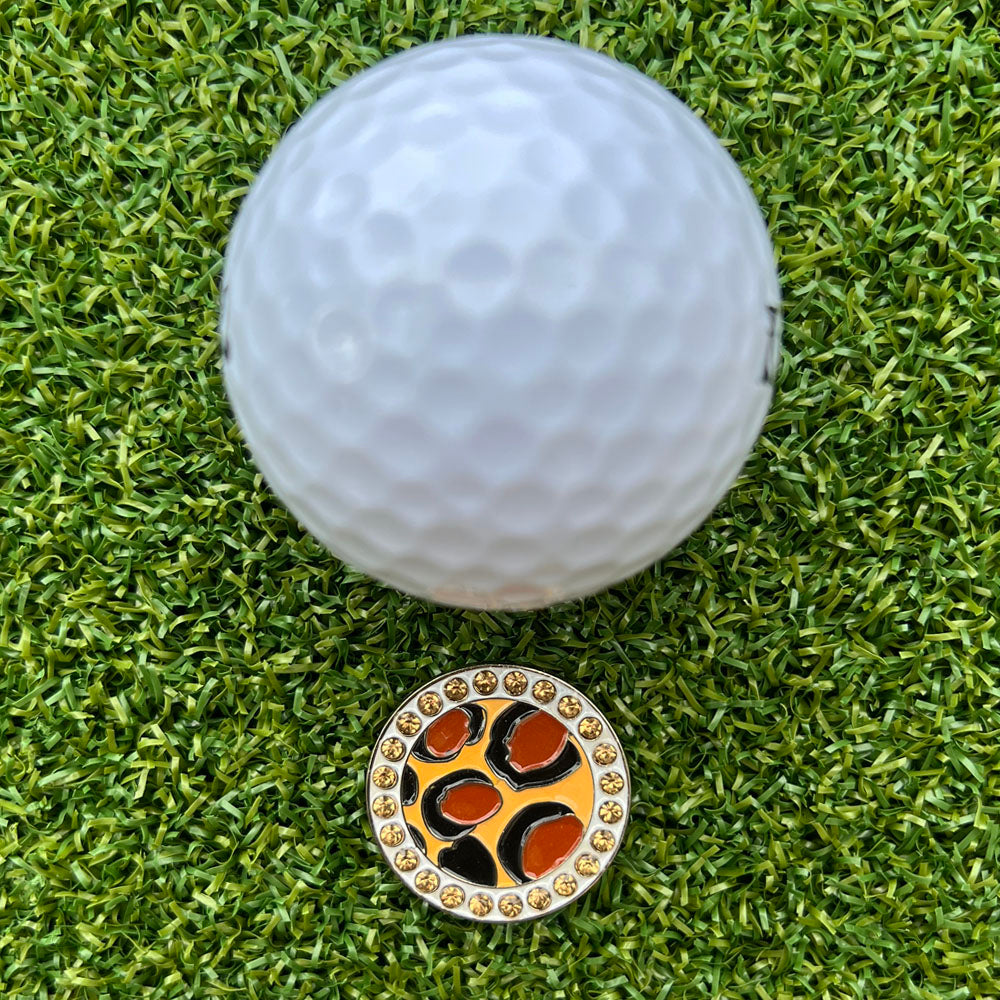 Golf ball with a leopard print golf ball marker on a green grass background