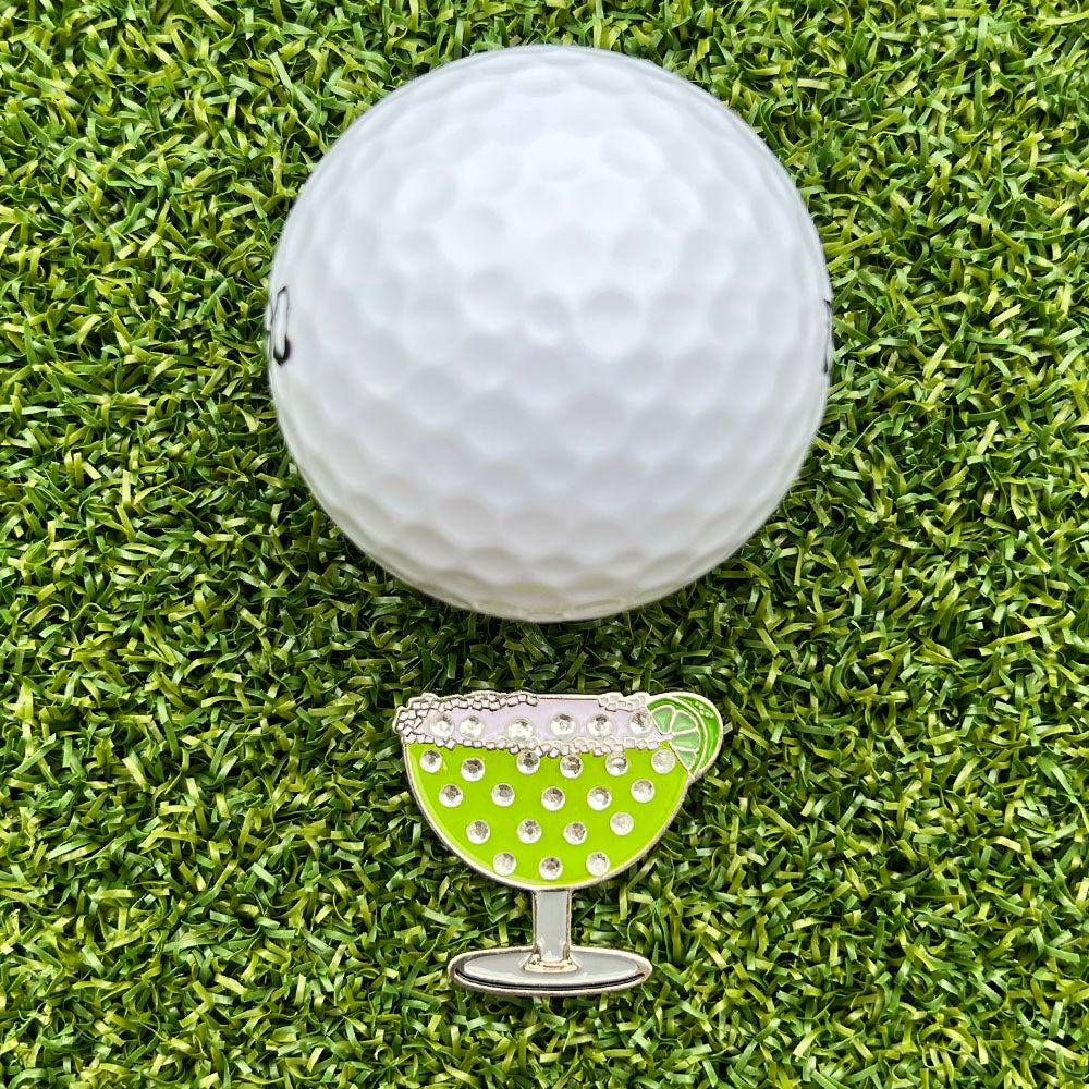 Golf ball with a green margarita glass ball marker on grass