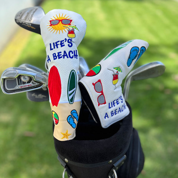 The Giggle Golf Life's A Beach utility club cover and blade putter cover on the golf course.