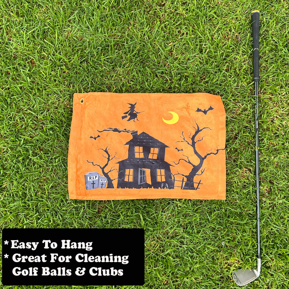 orange Halloween golf towel with text, next to a golf club on grass