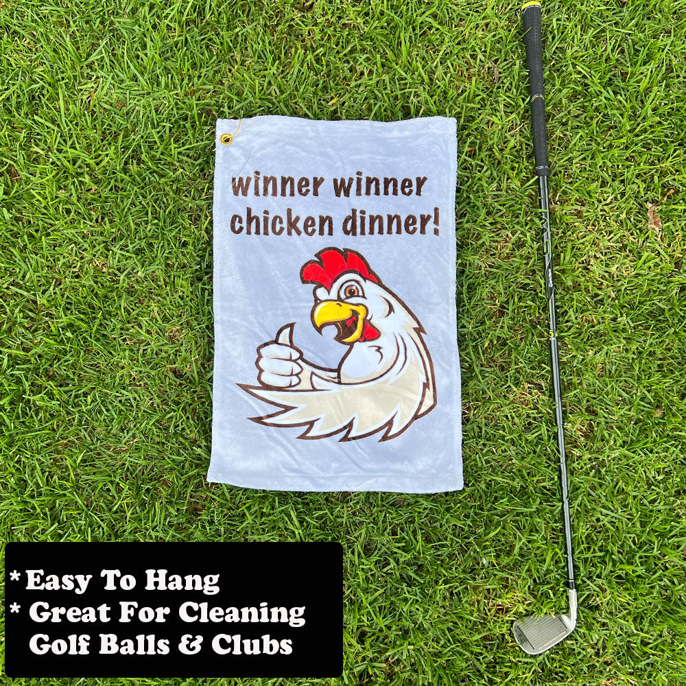 Golf towel with chicken graphic and text 'winner winner chicken dinner!' on grass, next to a golf club.
