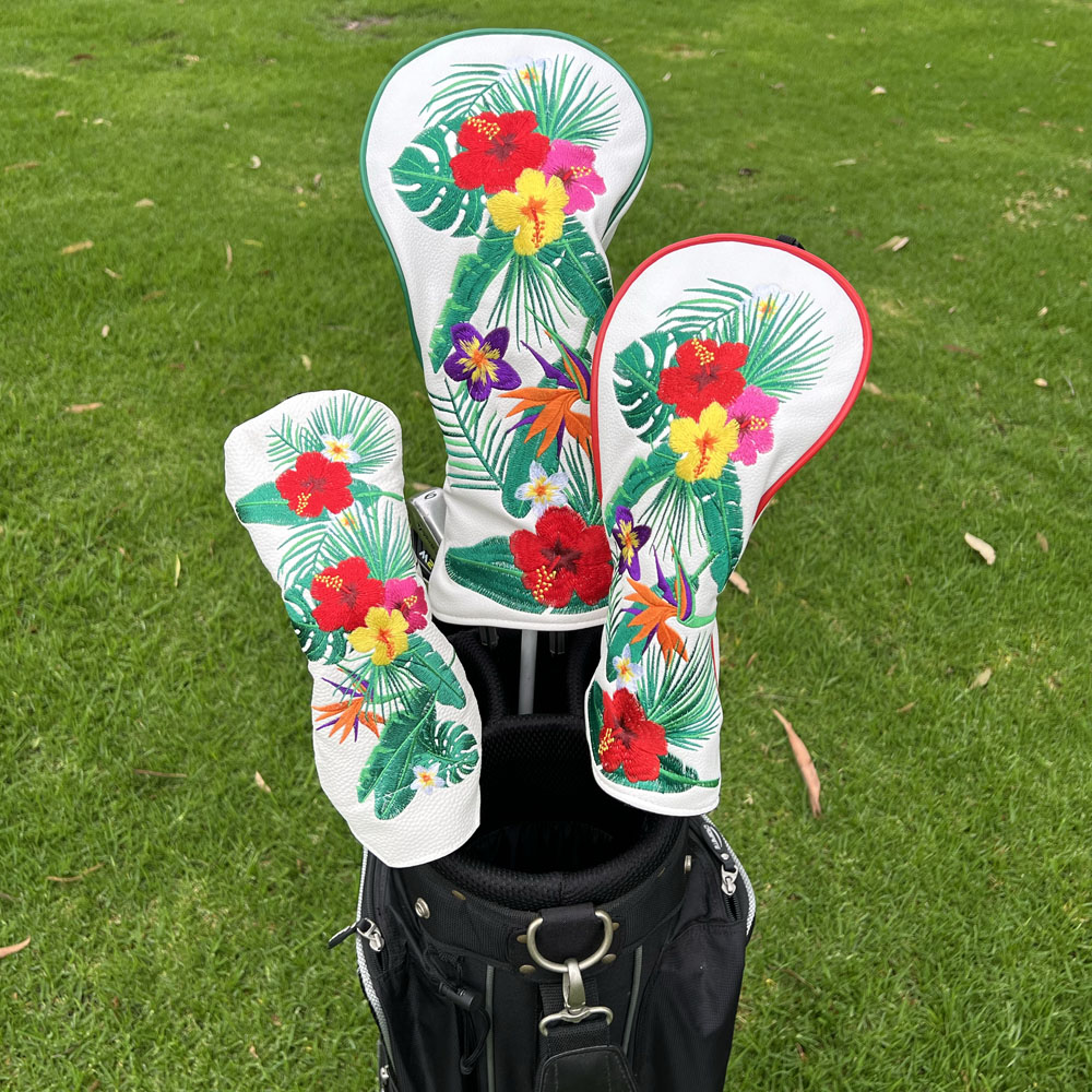 Golf club head covers (driver, 3 wood and hybrid) with tropical floral design on a golf bag against a grass background