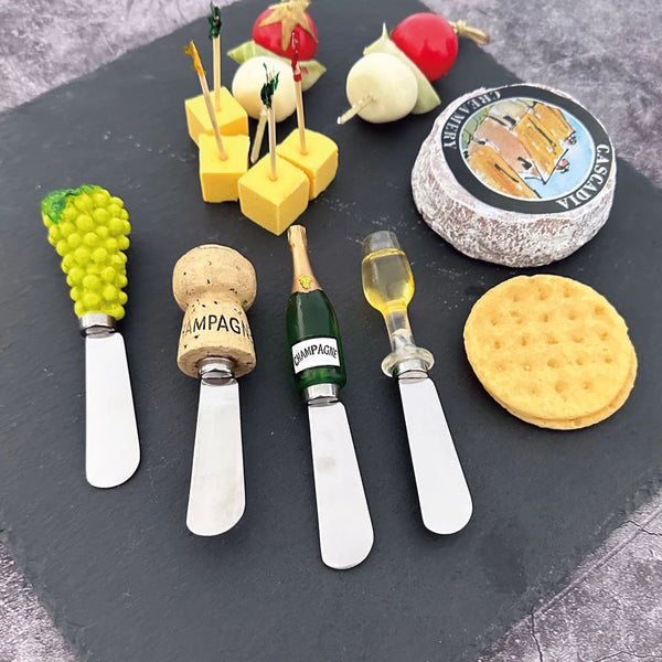 Champagne Themed Cheese Spreader Set Next To Cheese & Crackers