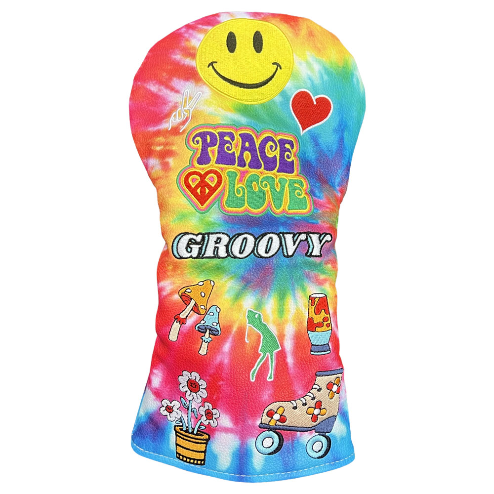 A tie-dye driver golf club headcover featuring a yellow smiley face, a red heart, the words 'PEACE LOVE GROOVY' in colorful retro lettering, and small retro illustrations including mushrooms, a frog, flowers, and roller skates on a white background.