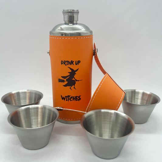 8 oz orange flask with 4 stainless steel shot glasses featuring a halloween design - a witch on her broomstick and text that says 'Drink Up Witches'