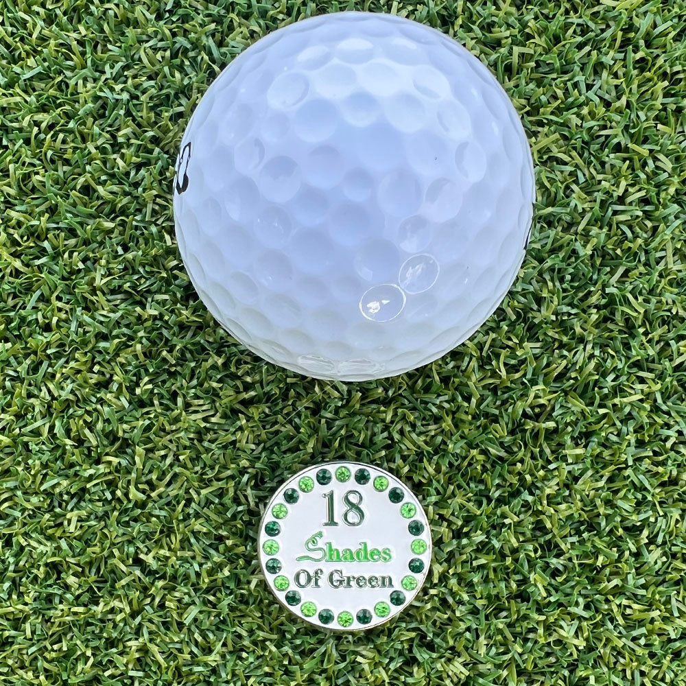 Golf ball on a grass surface with a '18 Shades of Green' bling golf ball marker.
