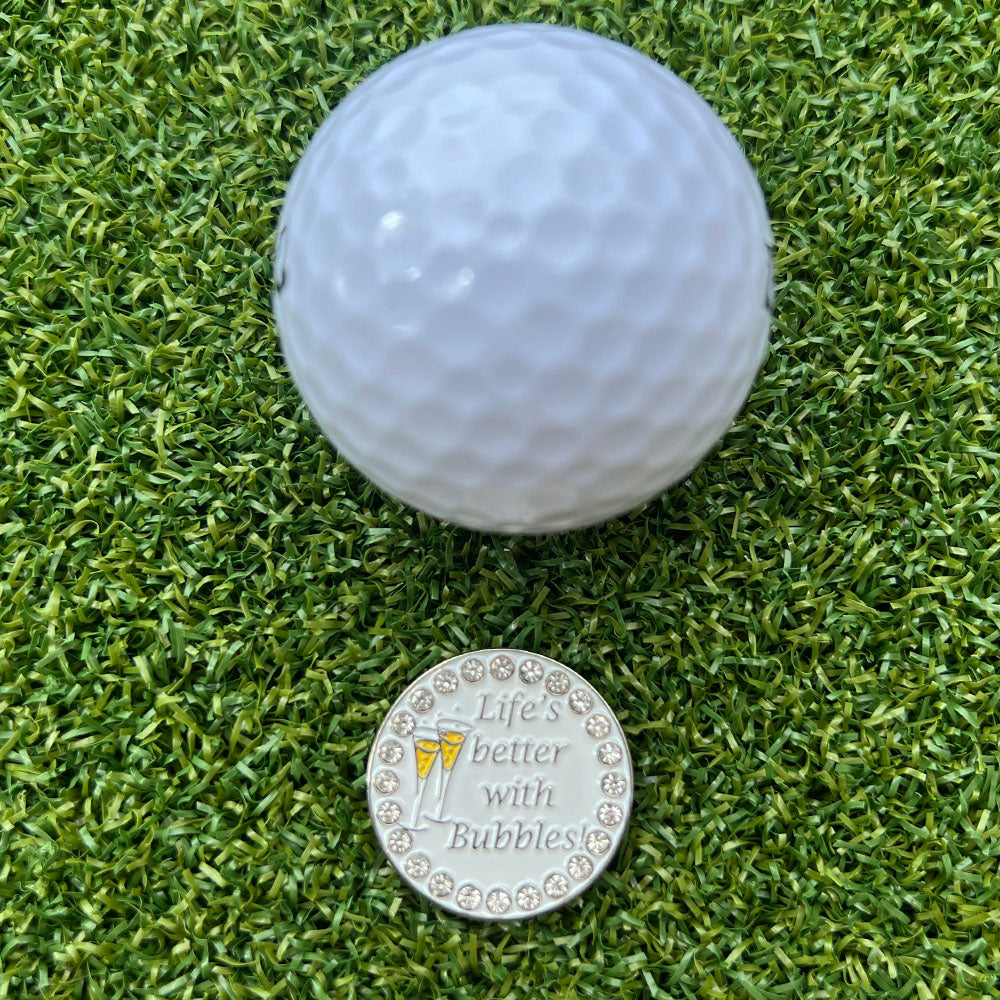golf ball on grass with a champagne themed ball marker