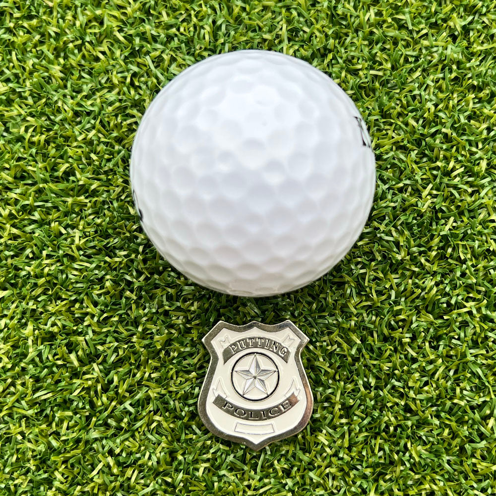 Golf ball on a green grass surface with a 'Putting Police' ball marker.