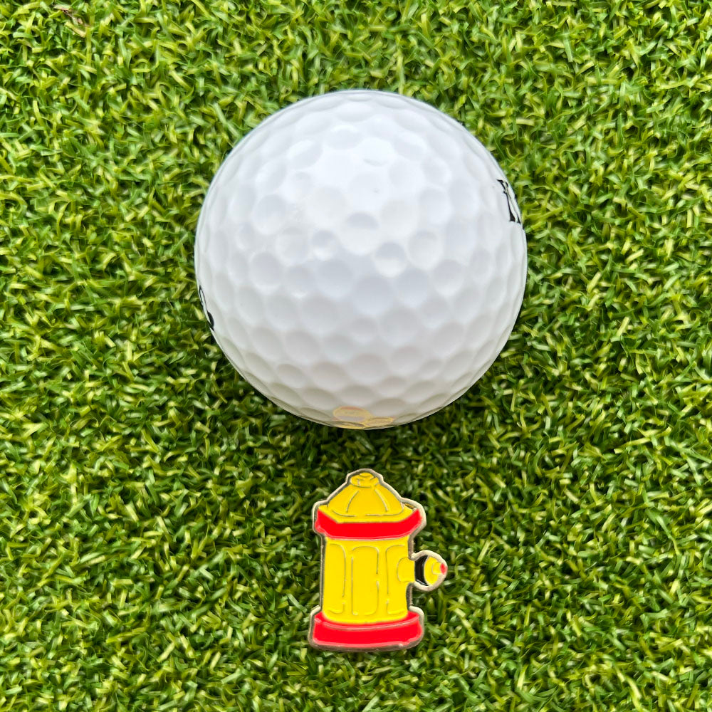Golf ball on grass with a yellow and red fire hydrant ball marker