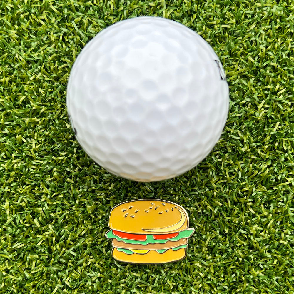Golf ball on grass with a hamburger-shaped ball marker