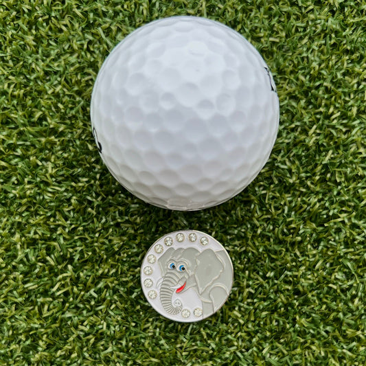 elephant themed ball marker with white golf ball on grass