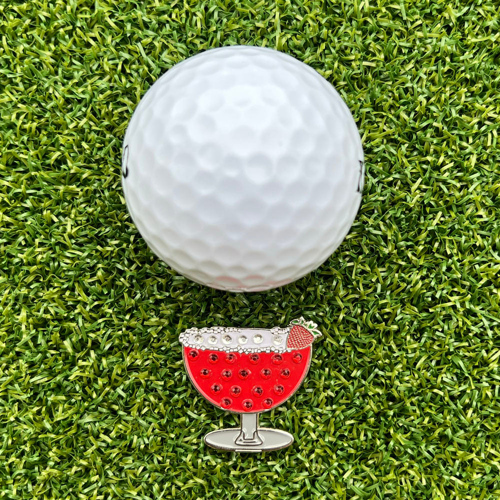 strawberry margarita shaped ball marker with white golf ball on grass