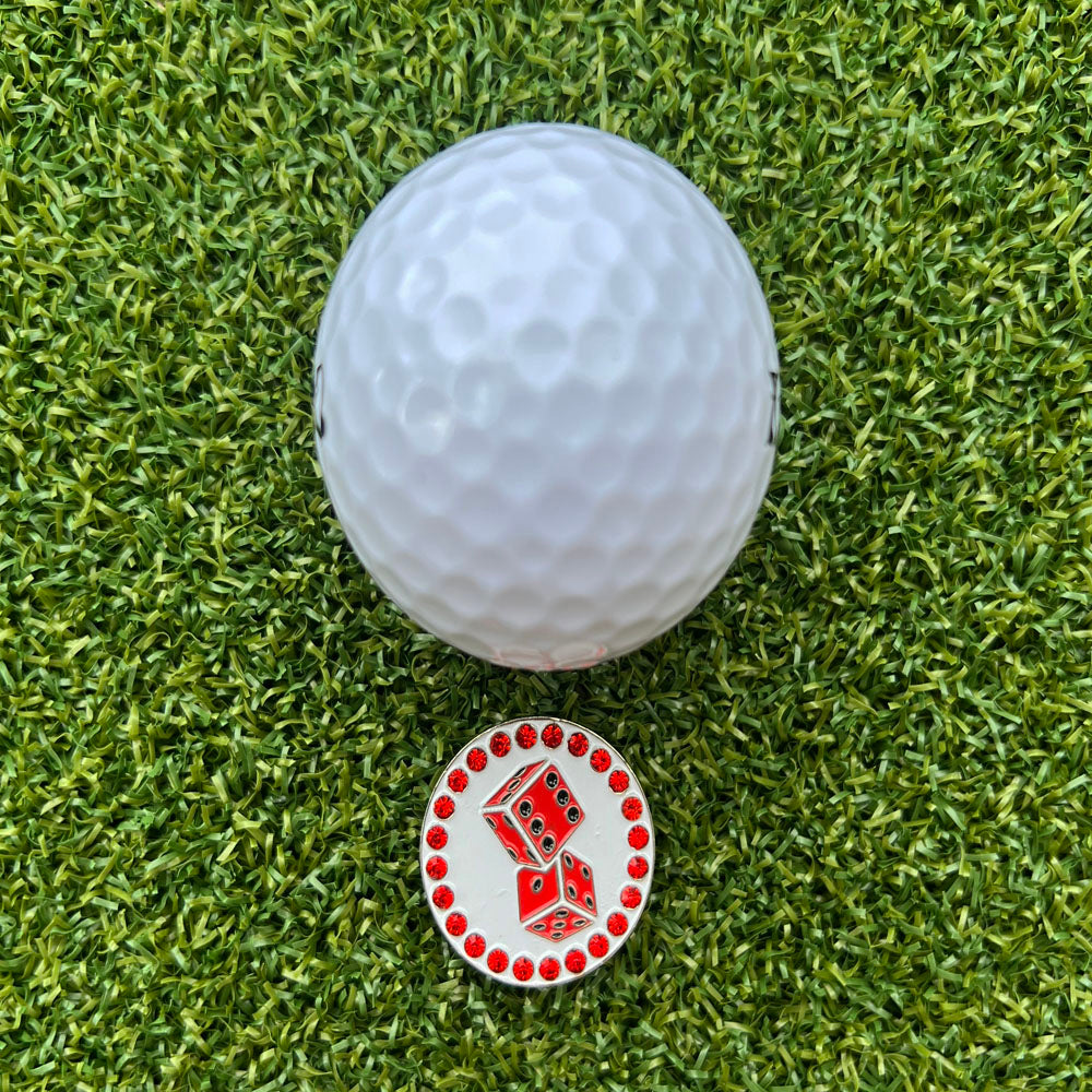 Golf ball on green grass with a red dice ball marker