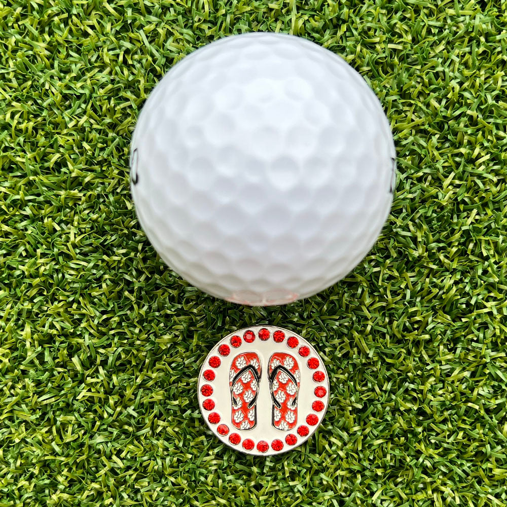 red and white flip flop ball marker on grass with a white golf ball