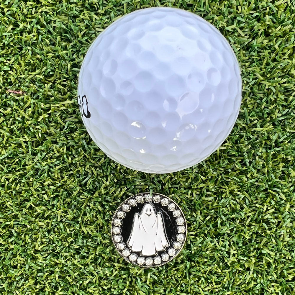 Golf ball with a ghost-themed golf ball marker on grass
