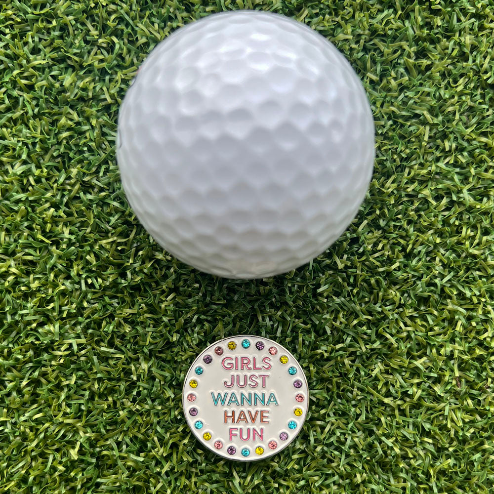 Girls Just Wanna Have Fun colorful golf ball marker next to a golf ball on grass