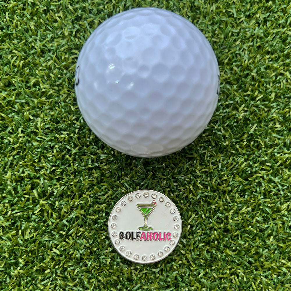 Golf ball on grass with a 'Golfaholic' martini ball marker