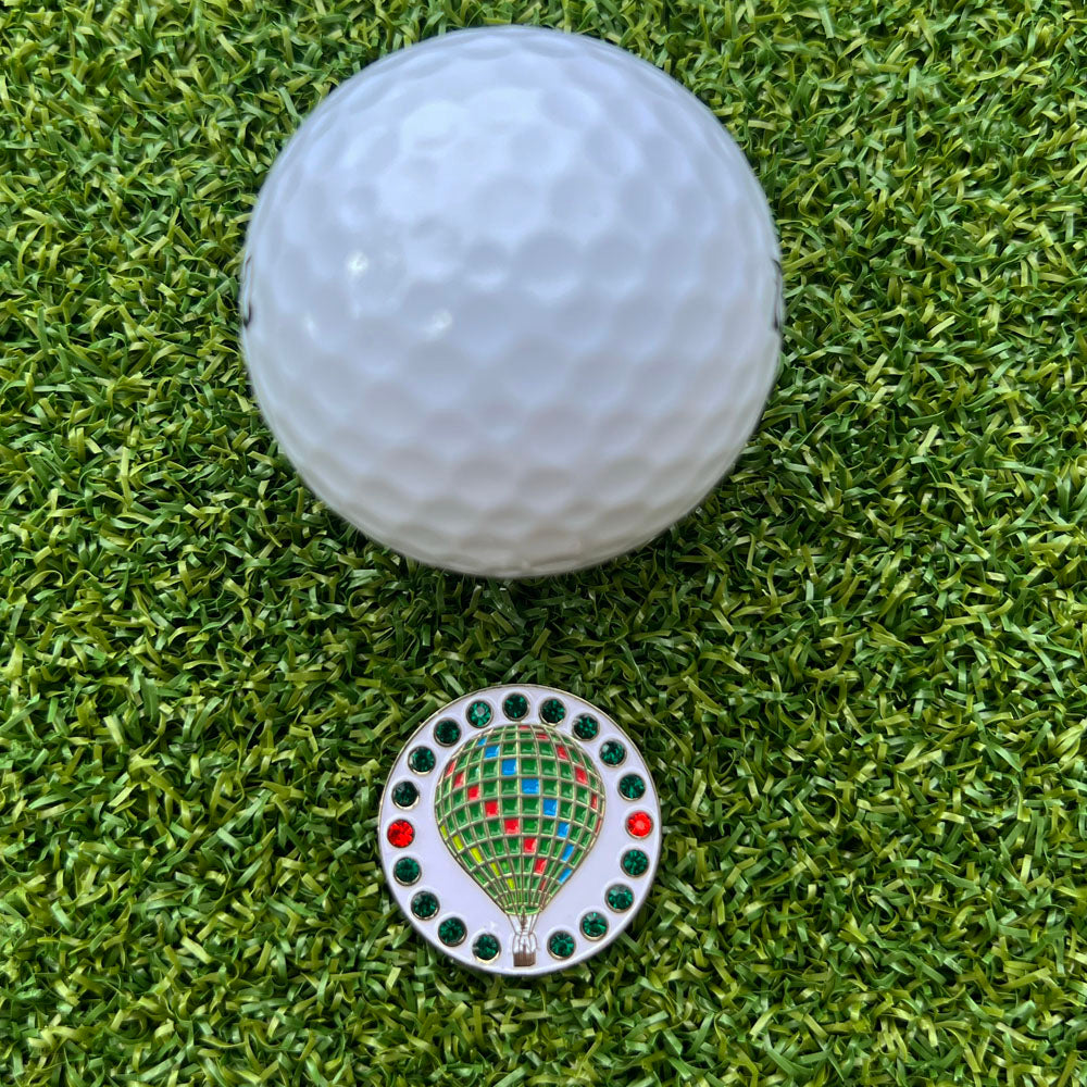 Golf ball on green grass with a colorful hot air balloon golf ball marker