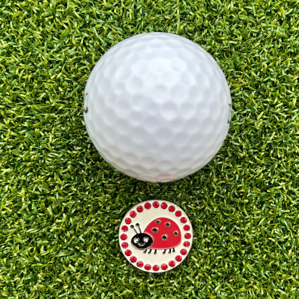 Golf ball on a green grass surface with a ladybug design ball marker.