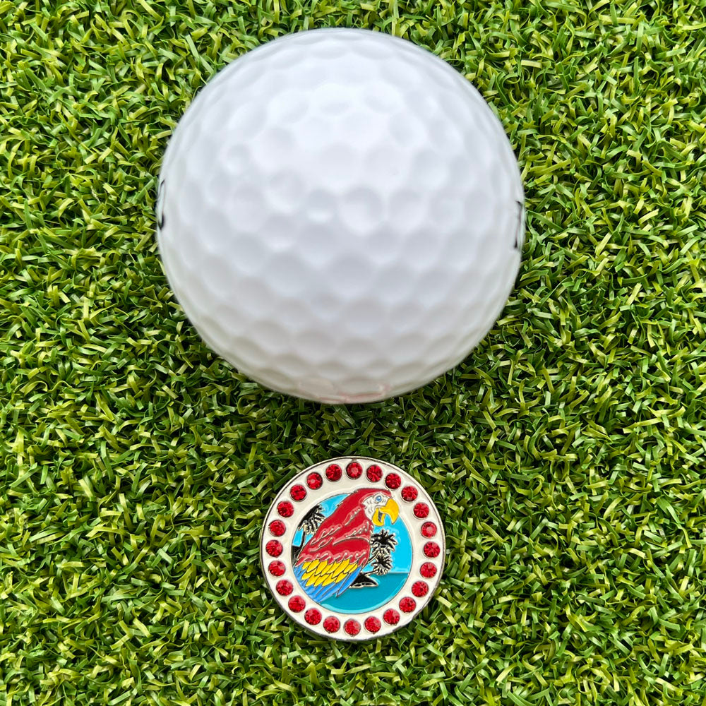 parrot with tropical background ball marker next to a white golf ball, on grass