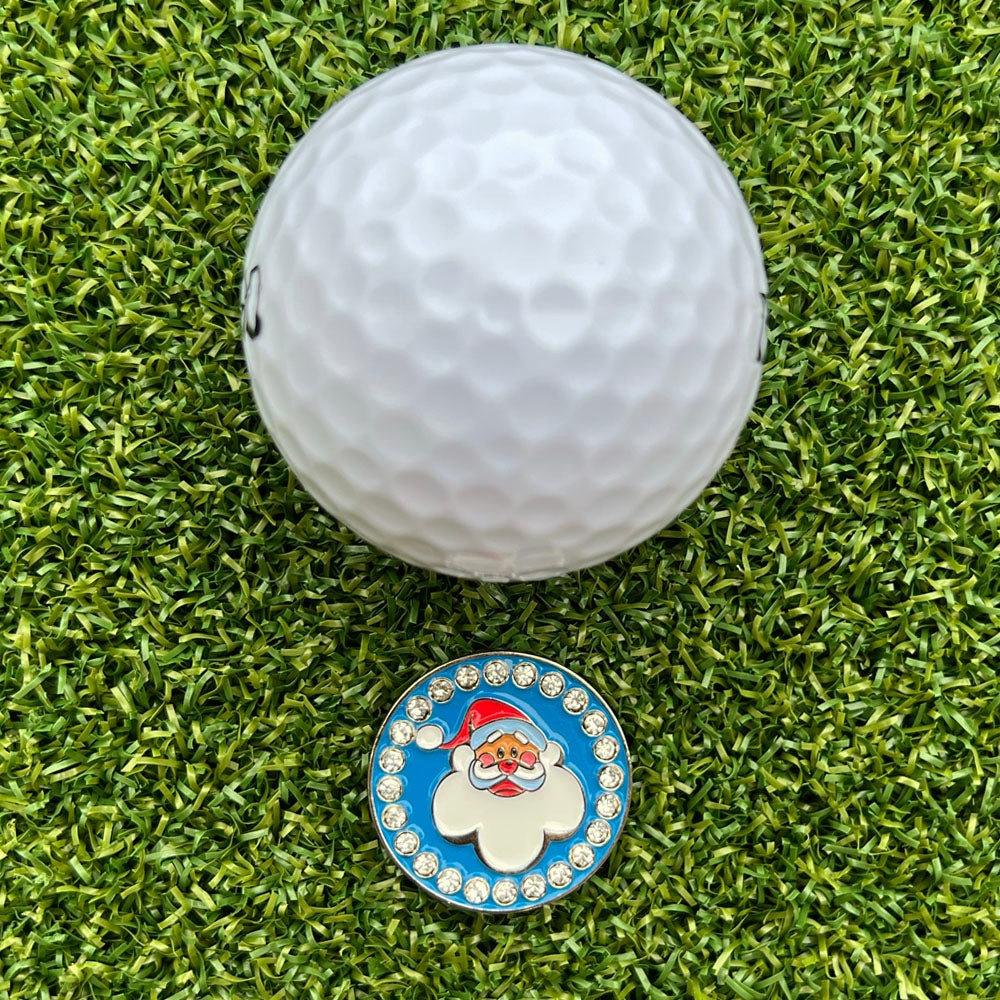 white golf ball on grass with santa-themed ball marker