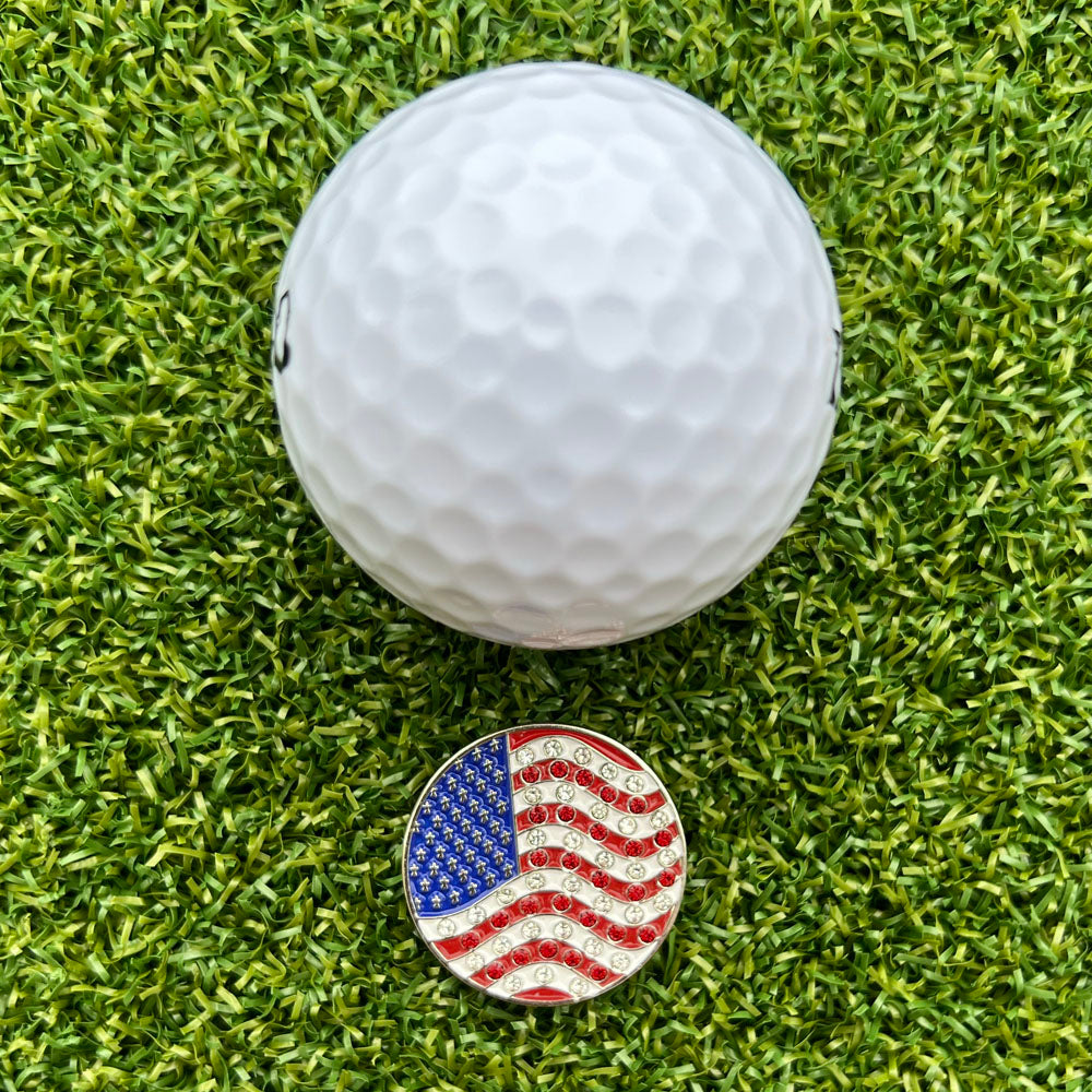 Golf ball on grass with an American flag golf ball marker.