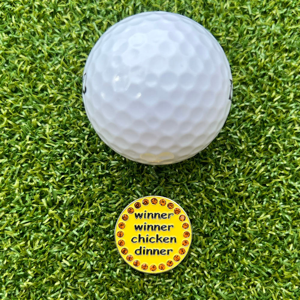 Golf ball with a 'winner winner chicken dinner' marker on a green grass background