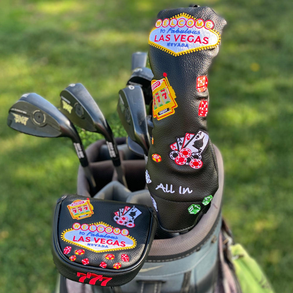 A Las Vegas hybrid head cover and mallet putter cover, on a grey golf bag that is on a golf course fairway.