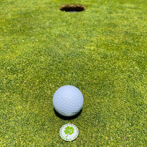 Giggle Golf Bling 4 Leaf Clover Ball Marker On A Putting Green, Behind A White Golf Ball