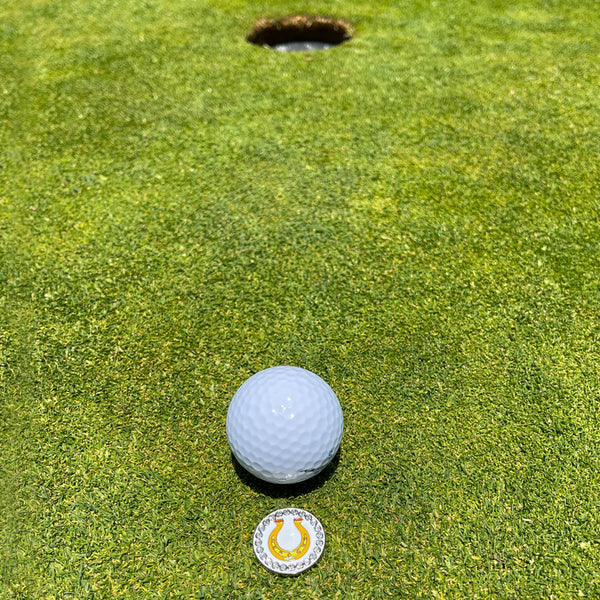 Giggle Golf Bling Horseshoe Ball Marker On The Putting Green, Behind A White Golf Ball