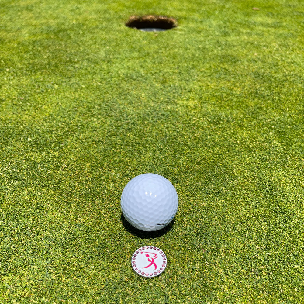 Giggle Golf Bling Breast Cancer Pink Ribbon Golfer Ball Marker On The Putting Green, Behind A White Golf Ball