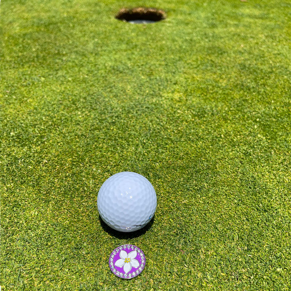 Giggle Golf Bling Plumeria Ball Marker On A Putting Green, Behind A White Golf Ball