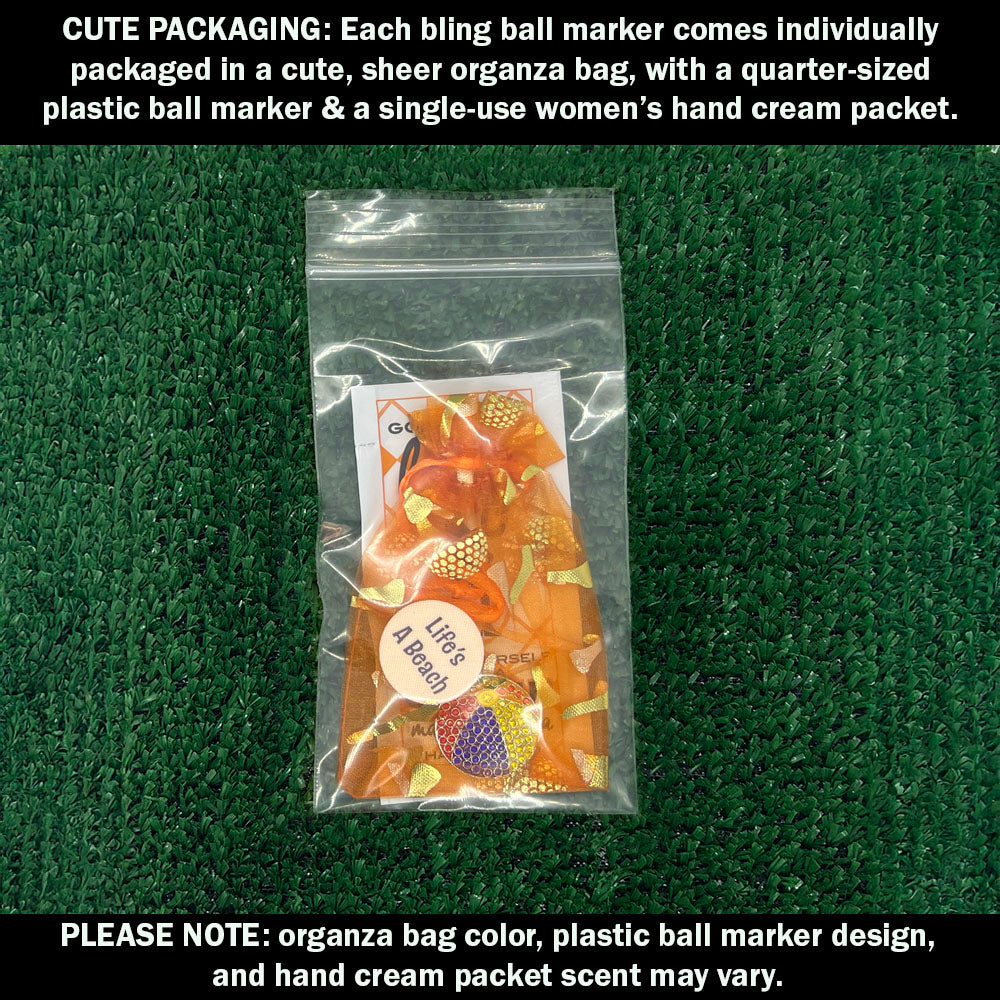 Cute packaging with bling beach ball ball marker, plastic ball marker, and hand cream packet on a green textured background.