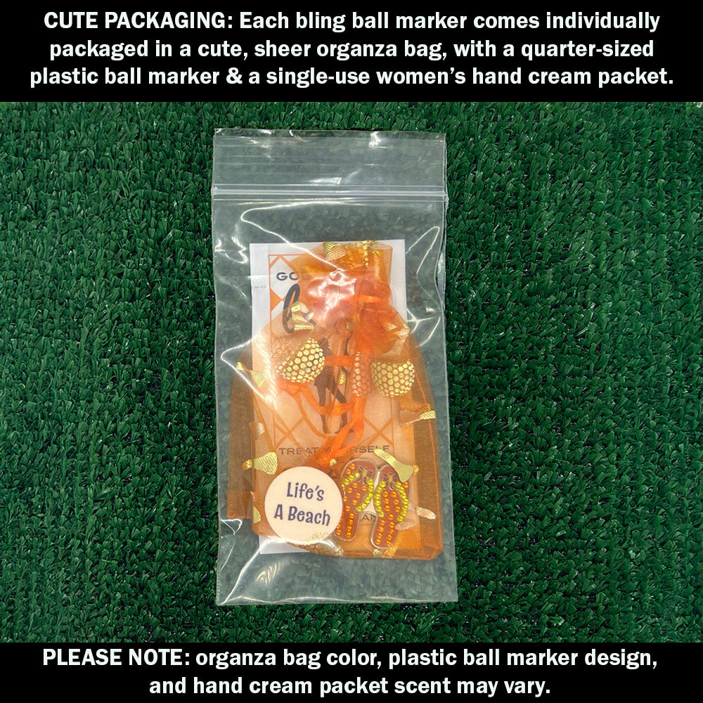 Cute packaging with bling orange flip flops ball marker, plastic ball marker, and hand cream packet on a green textured background.