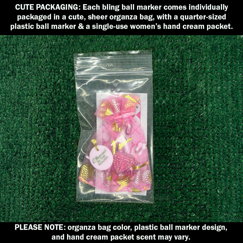 Cute packaging with bling pink diamond ball marker, plastic ball marker, and hand cream packet on a green textured background.