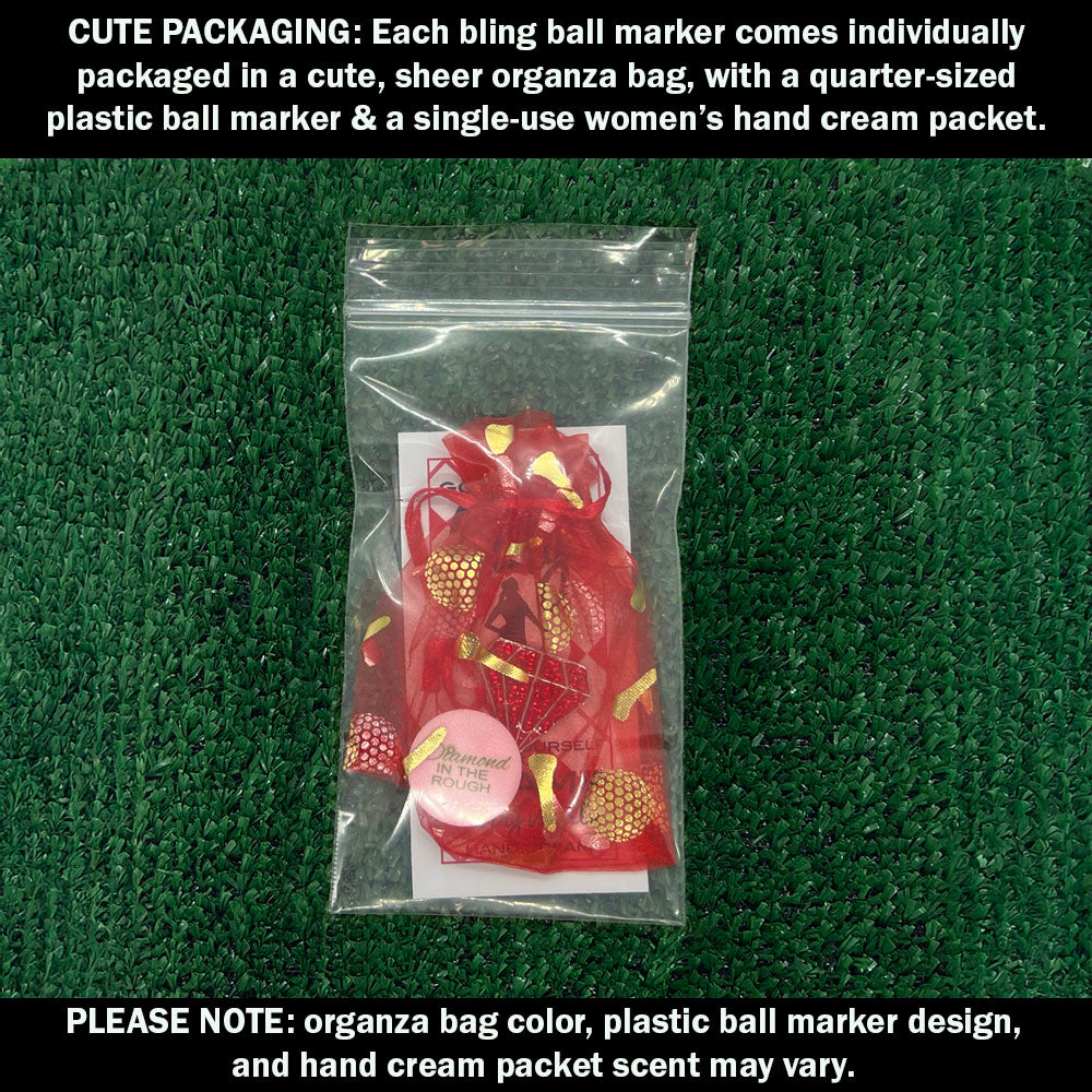 Cute packaging with bling red diamond ball marker, plastic ball marker, and hand cream packet on a green textured background.