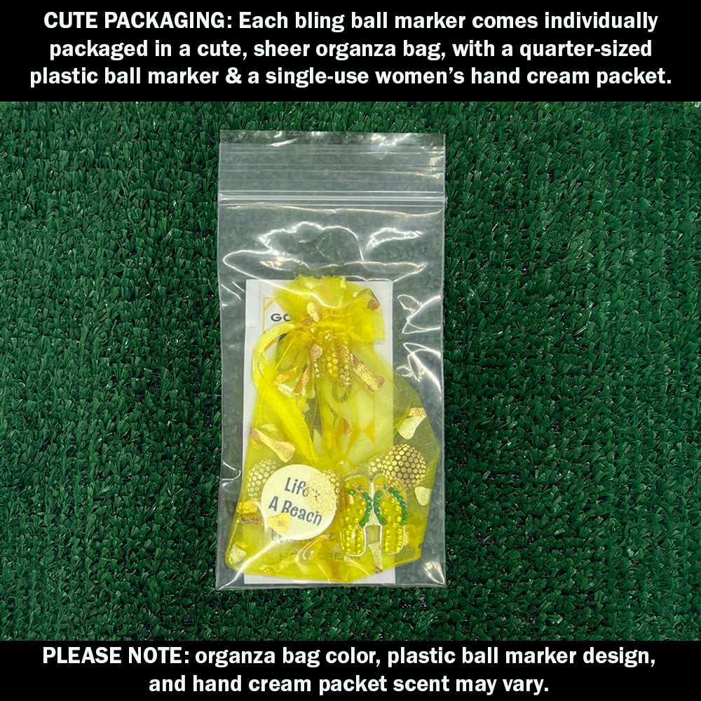 Cute packaging with a yellow flip flops bling ball marker, plastic ball marker, and hand cream packet on a green textured background.