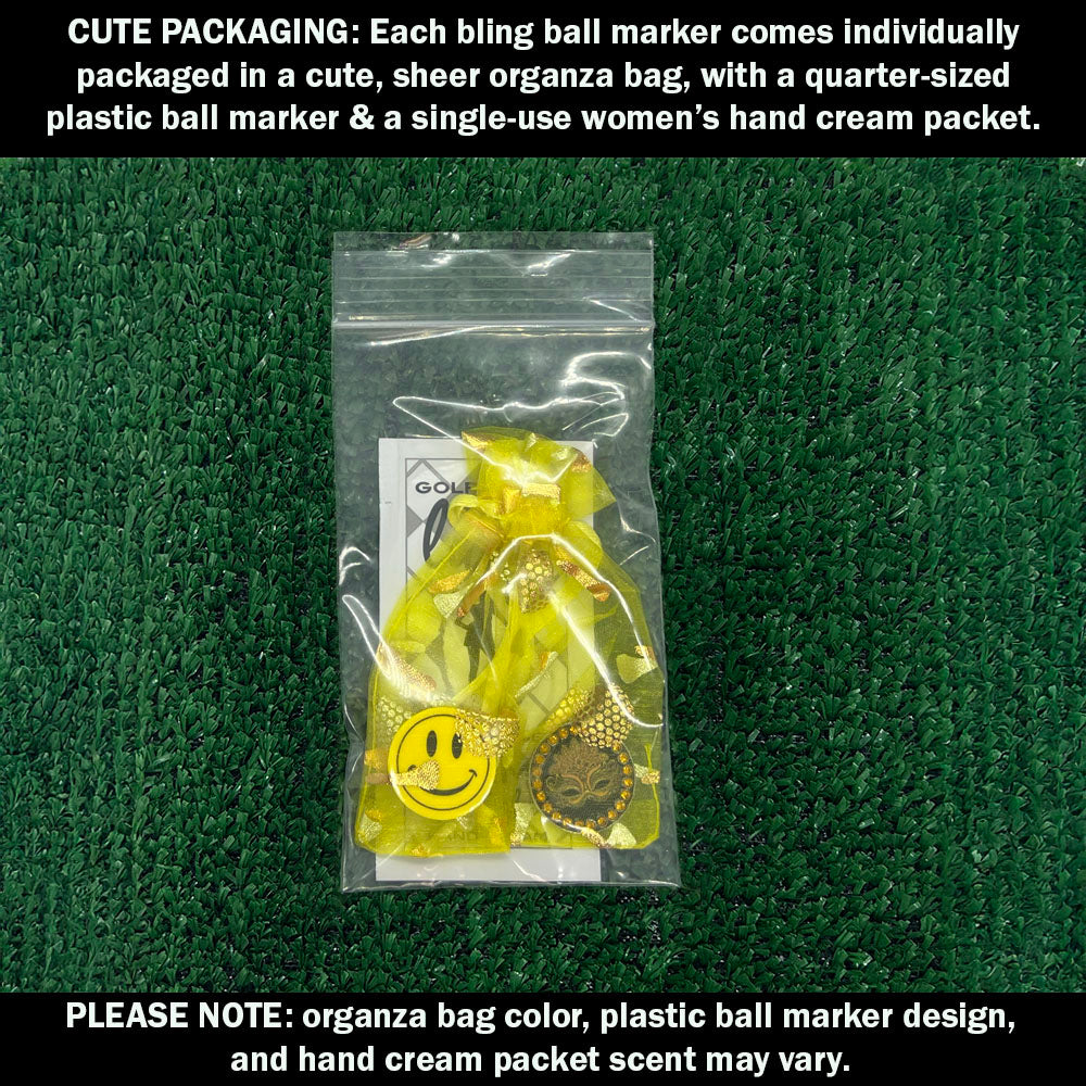 Cute packaging with bling mask ball marker, plastic ball marker, and hand cream packet on a green textured background.