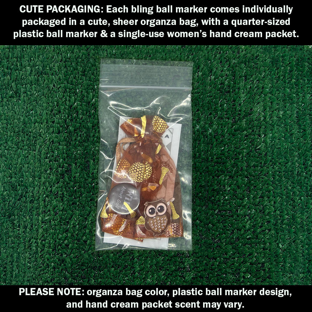 Cute packaging with bling owl ball marker, plastic ball marker, and hand cream packet on a green textured background.