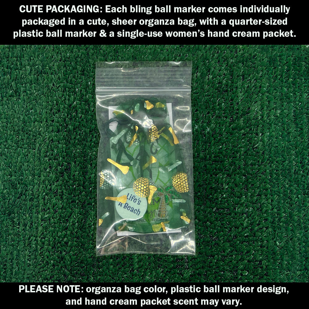 Cute packaging with bling palm tree ball marker, plastic ball marker, and hand cream packet on a green textured background.