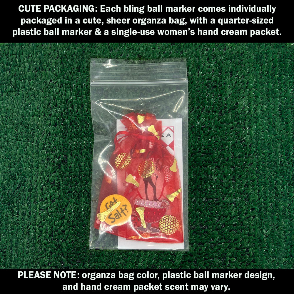 Cute packaging with bling red margarita ball marker, plastic ball marker, and hand cream packet on a green textured background.