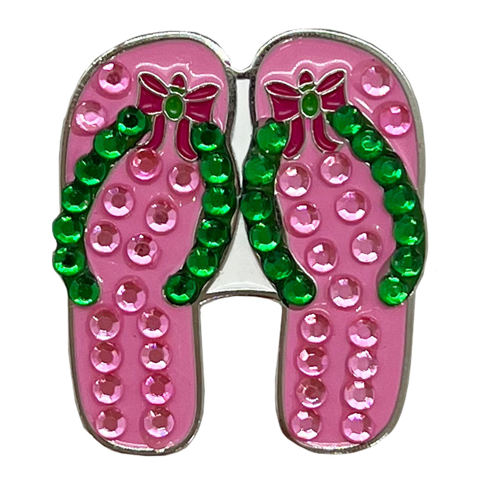 Golf ball marker, pink flip-flop shoes with green straps and rhinestones on a white background