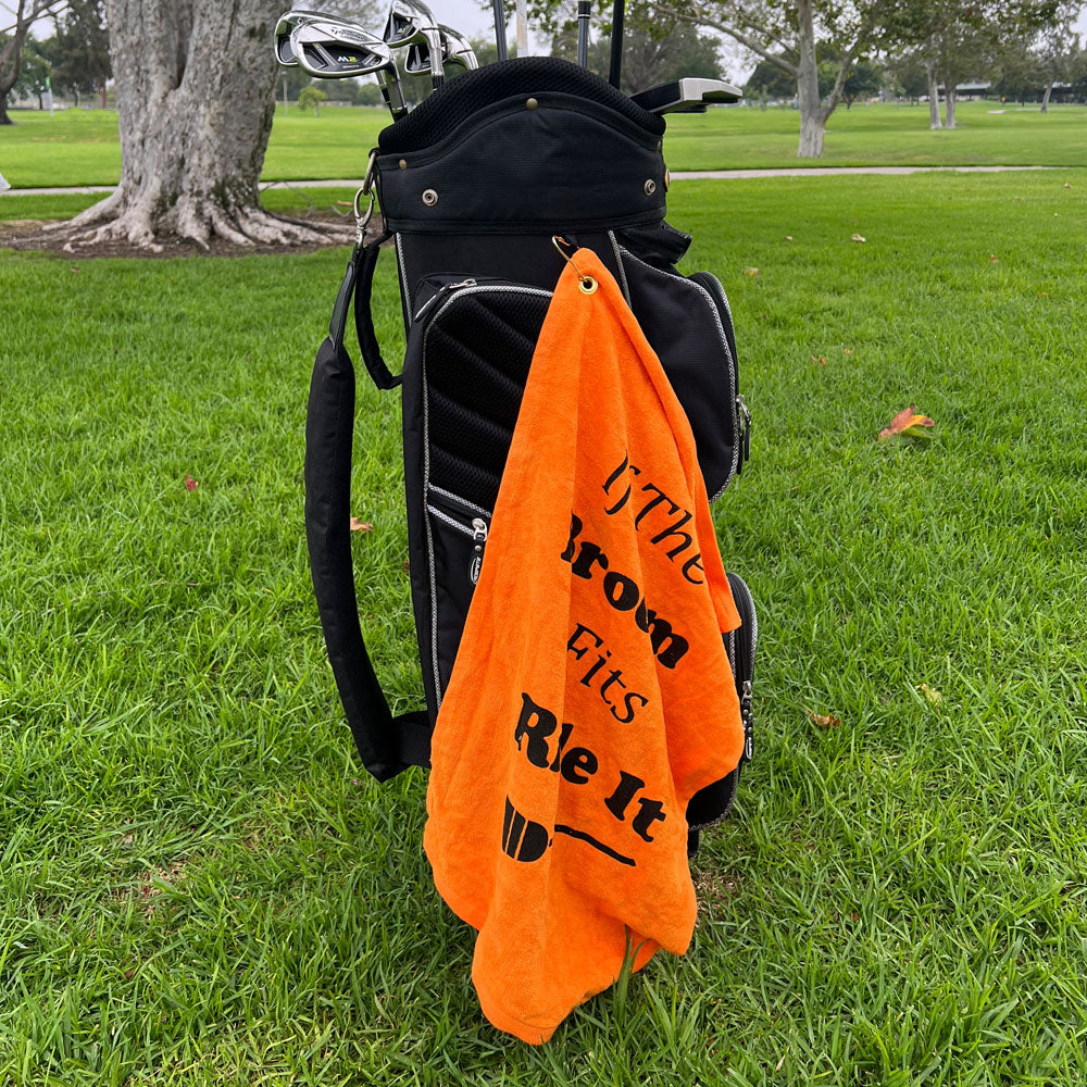 Golf bag with an orange Halloween towel hanging on it in a grassy area