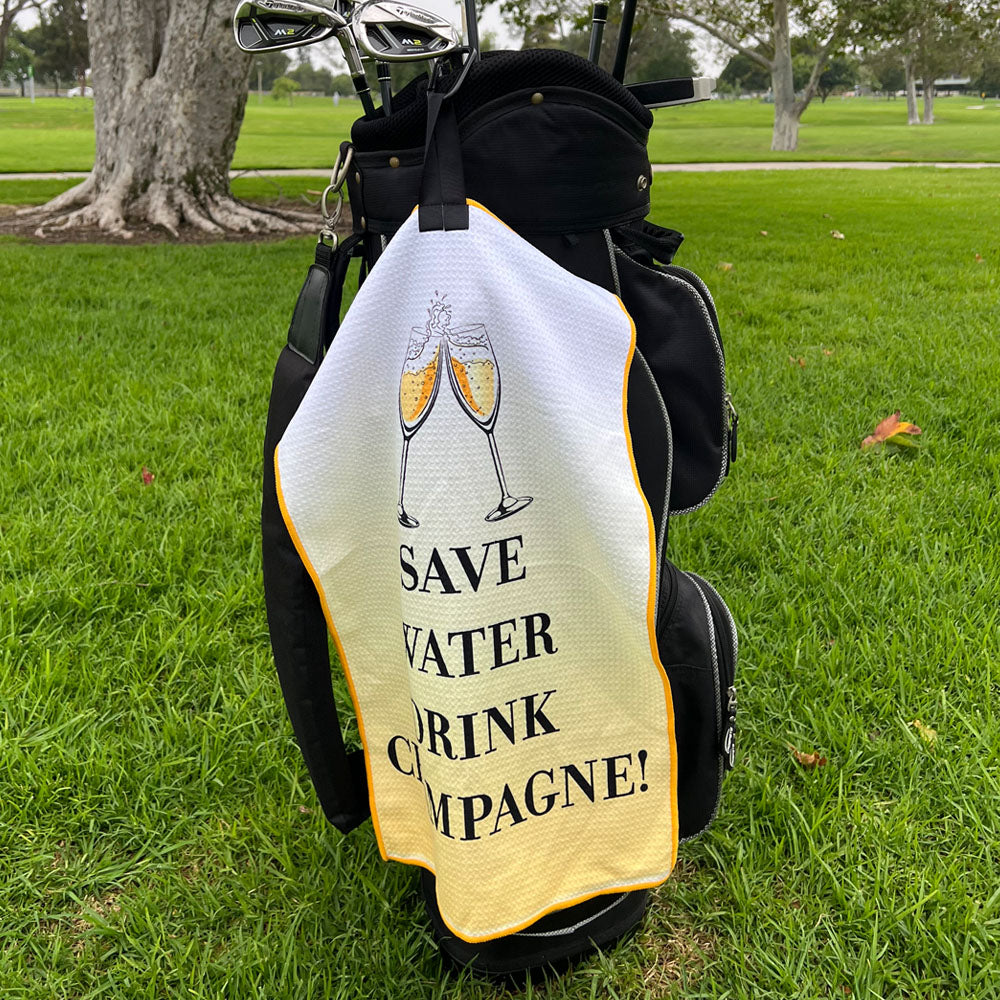 Golf bag with a humorous cover featuring champagne glasses and text on a grassy background
