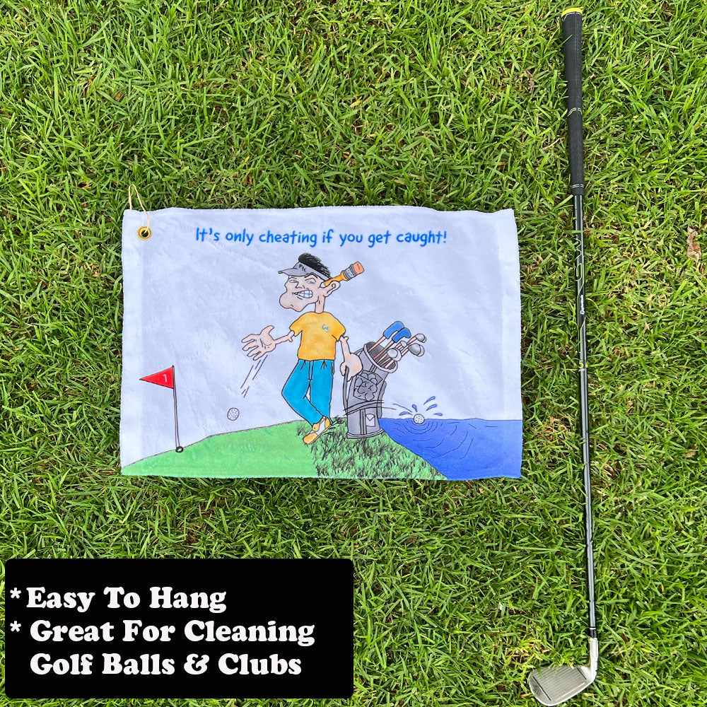 Golf towel with humorous design on grass next to a golf club