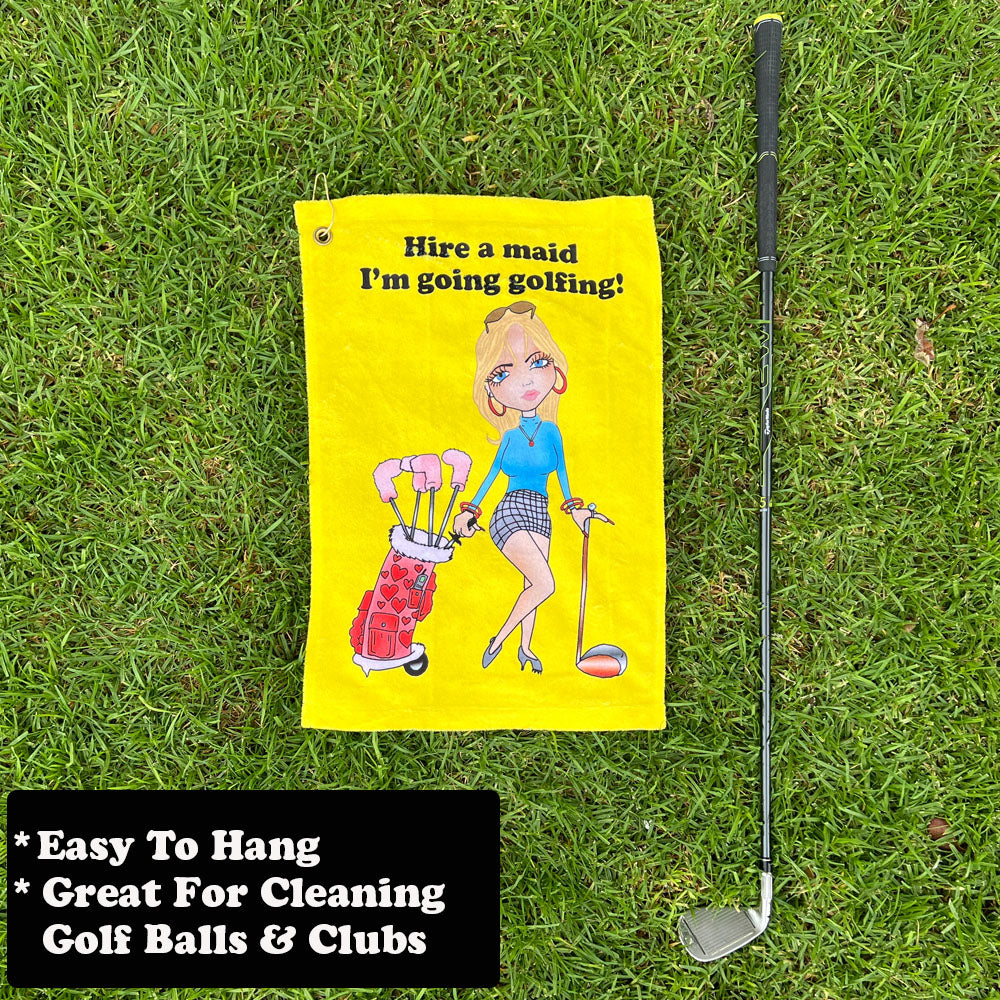 yellow golf towel with female golfer cartoon next to golf club on grass
