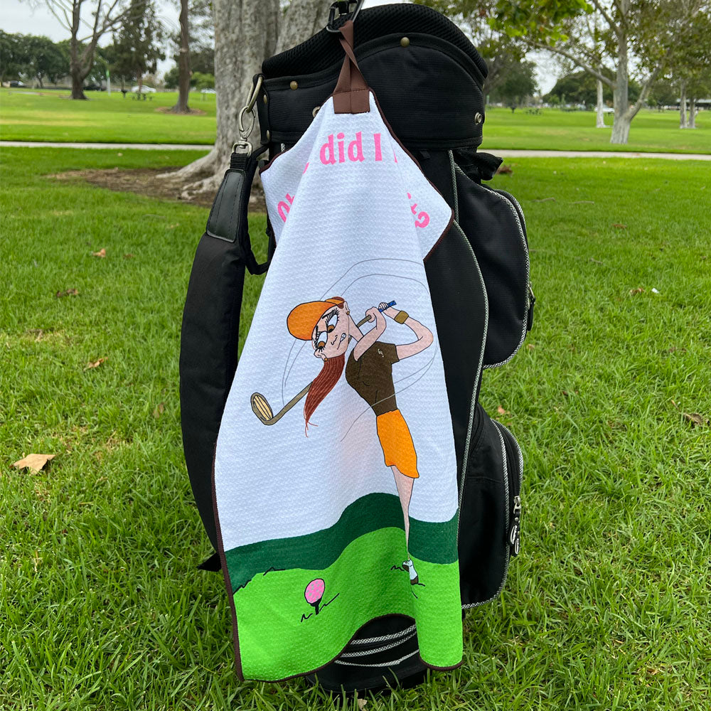 Golf towel with female golfer cartoon character on a golf bag on grass