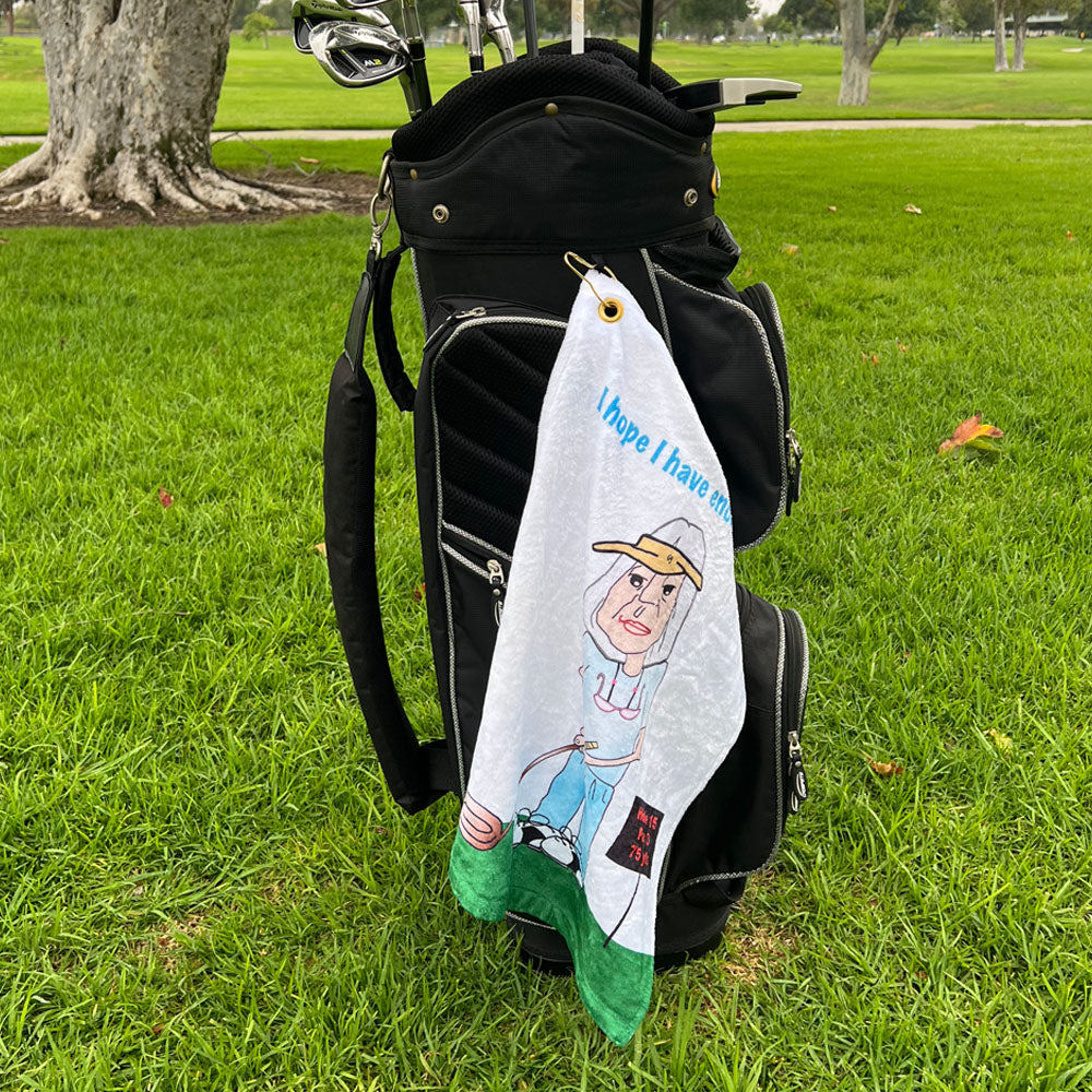Golf towel with cartoon character female golfer hanging from a golf bag on a grassy background